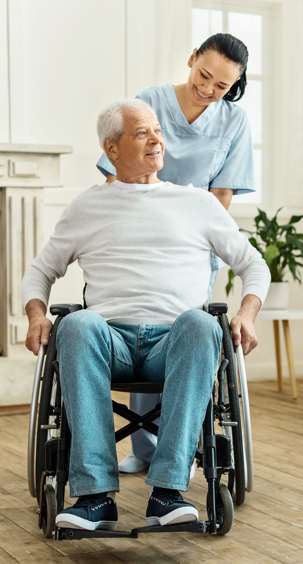 senior-in-wheelchair-with-nurse Senior man in wheelchair being pushed by nurse caregiver in his home